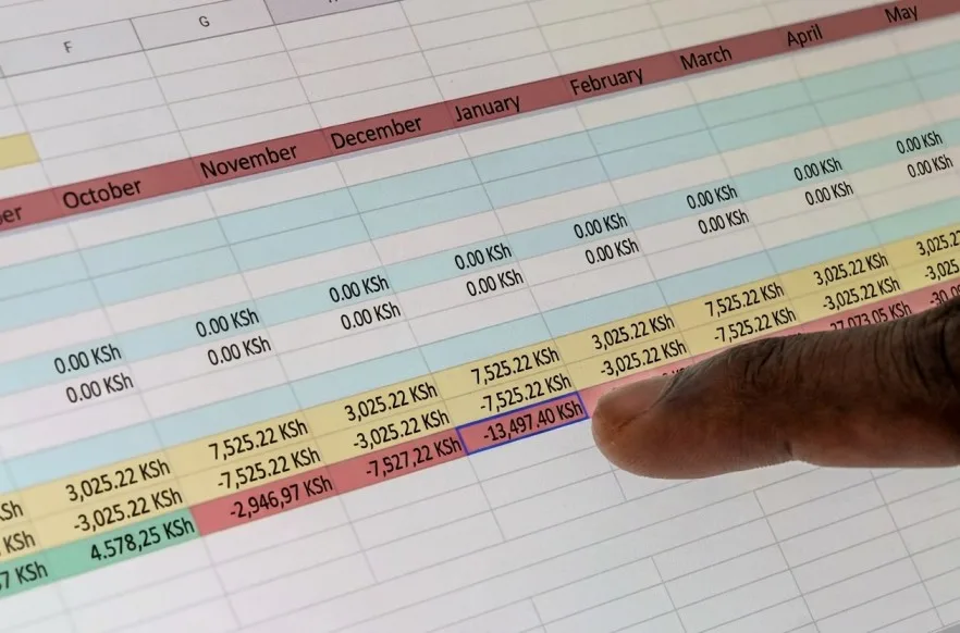 A finger pointing at a row in a printed spreadsheet of figures