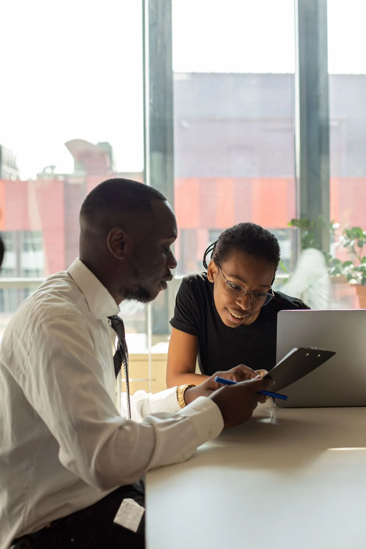 Two colleagues working together over a laptop and notes in a bright Nairobi office.